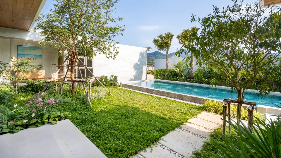 Garden lawn and lap pool beside the villa, with palms and hills behind