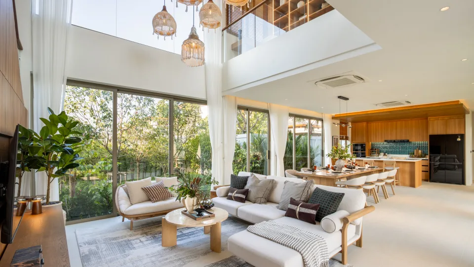 Double-height living room with sofas, a dining table and an open kitchen behind